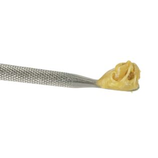 Close-up of beige cannabis concentrate on a metal dab tool against a white background.