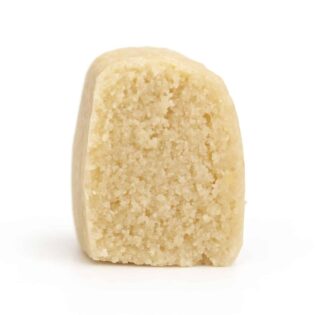 Close-up photorealistic image of a single beige edible product piece with a crumbly interior standing upright on a crisp white background.