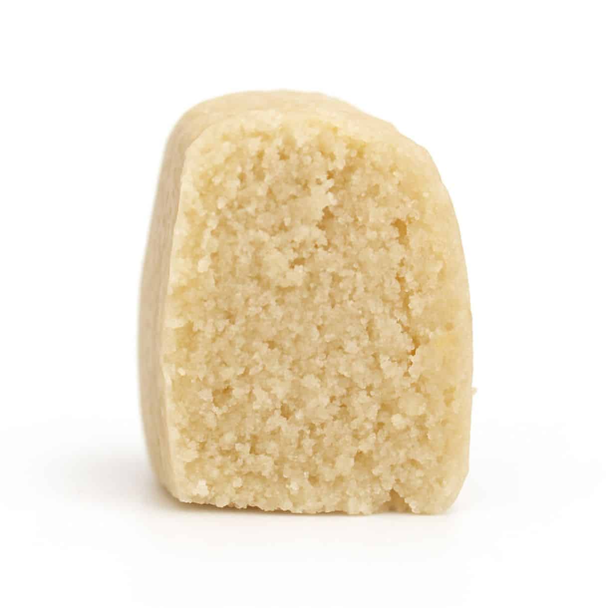 Close-up photorealistic image of a single beige edible product piece with a crumbly interior standing upright on a crisp white background.