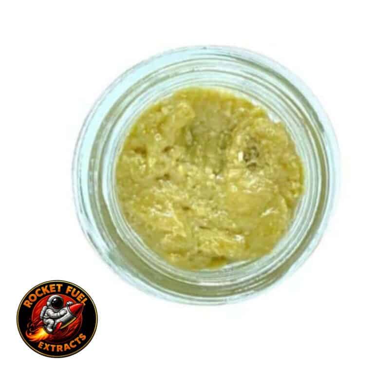 Open container of light-golden cannabis concentrate with a creamy, whipped texture on a white background.
