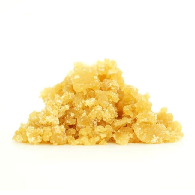 Golden cannabis sugar wax concentrate photographed on a crisp white background with visible crystal texture and natural depth