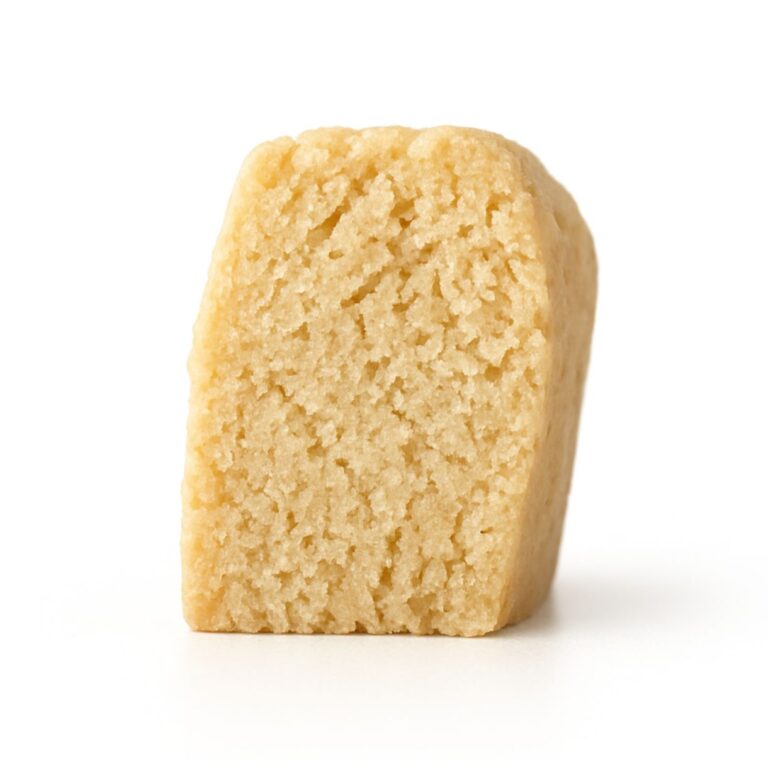 Close-up photo of a shortbread cookie piece standing upright on a crisp white background.