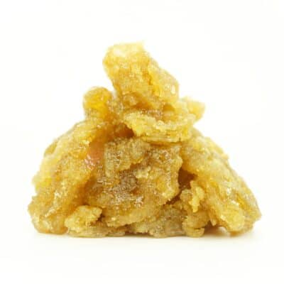 Close-up image of golden cannabis concentrate with a rich, glossy, and crystalline texture, piled in a small mound on a clean white background.