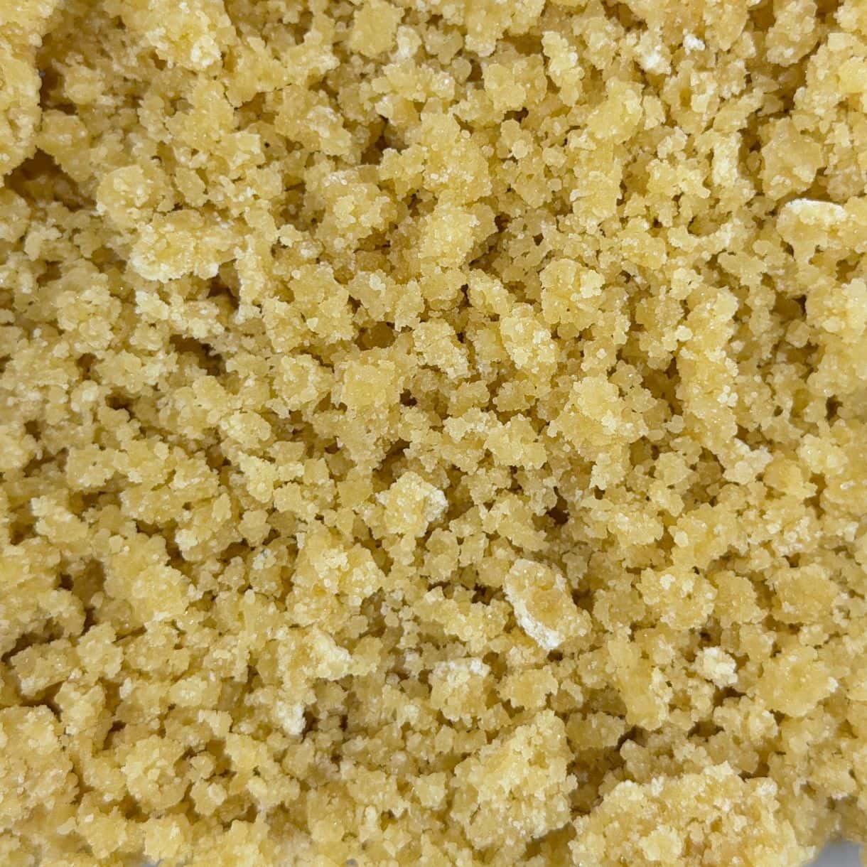 Open jar with golden, crumbly texture and granular consistency (close-up)