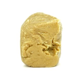 Close-up of a golden-brown cannabis concentrate chunk with a smooth, textured surface on a white background