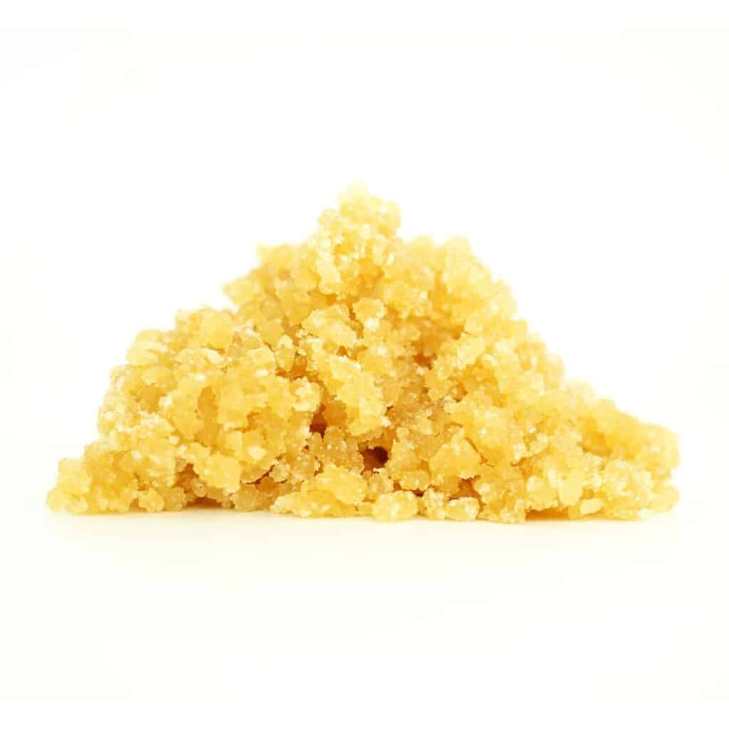 Golden cannabis sugar wax concentrate photographed on a crisp white background with visible crystal texture and natural depth