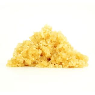 Golden cannabis sugar wax concentrate photographed on a crisp white background with visible crystal texture and natural depth