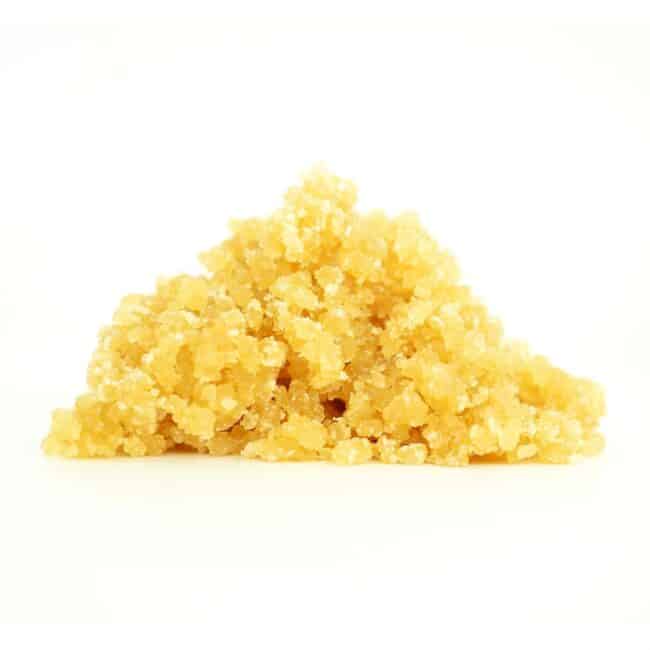 Golden cannabis sugar wax concentrate photographed on a crisp white background with visible crystal texture and natural depth