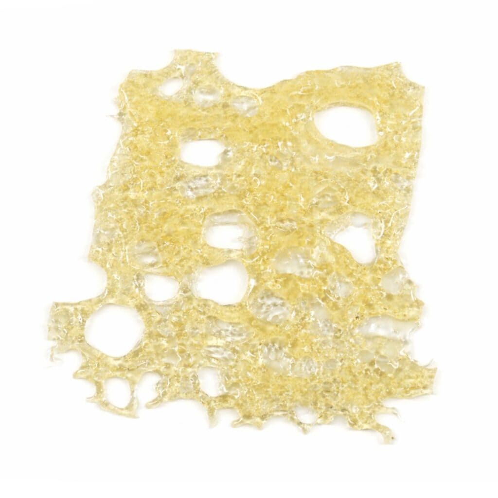 Close-up of a translucent golden cannabis concentrate slab with a porous, lace-like texture on a crisp white background.