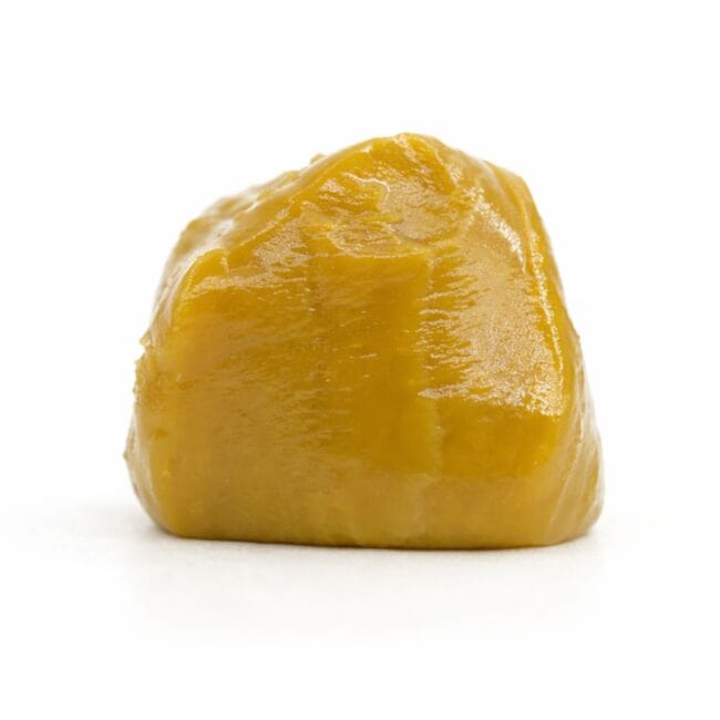 Golden yellow cannabis concentrate isolated on a white background, showing smooth texture and rounded form