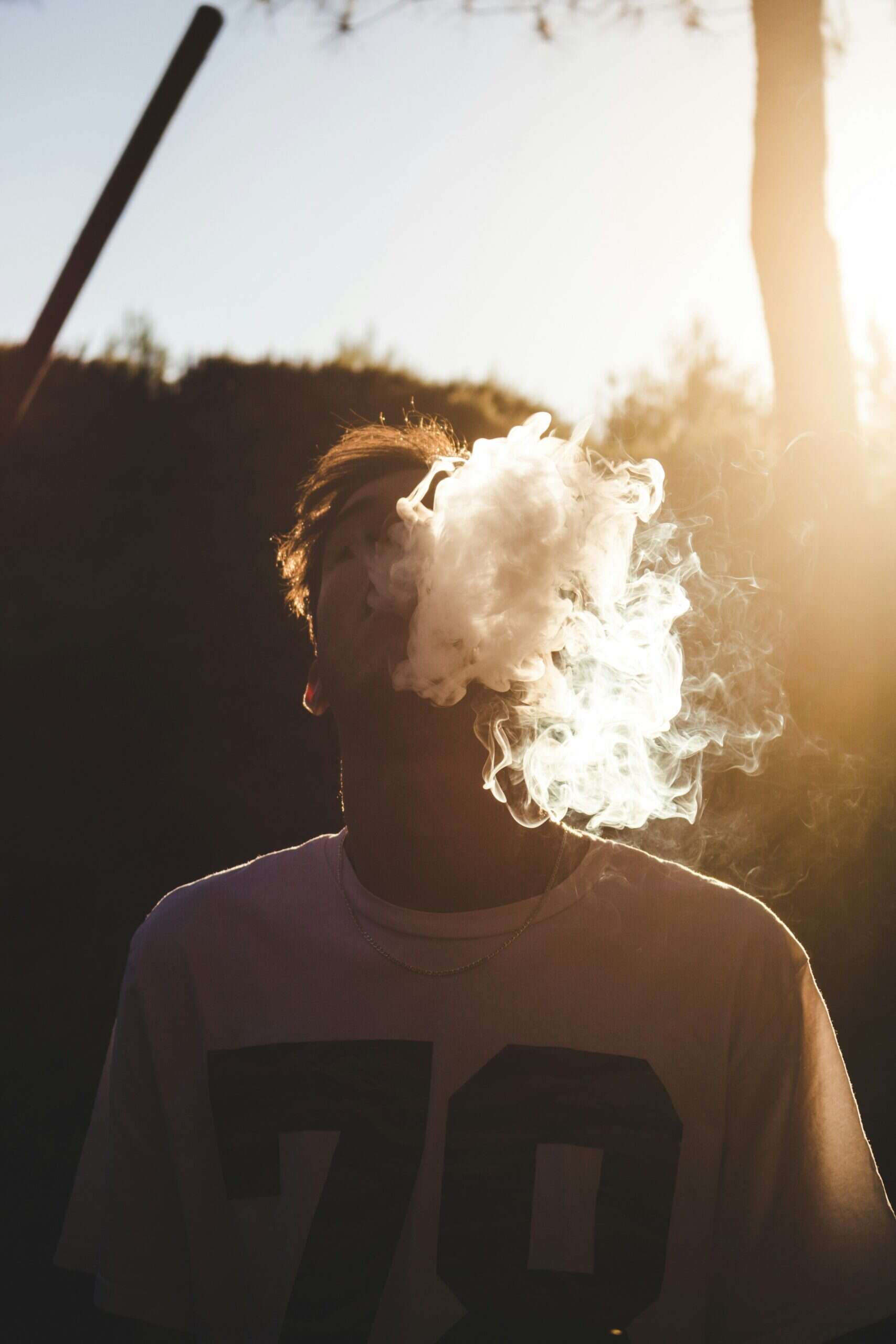daniel ramos suUs21vrCXc unsplash A young man exhales a thick cloud of smoke outdoors at sunset. Image by Daniel Ramos on Unsplash.com.