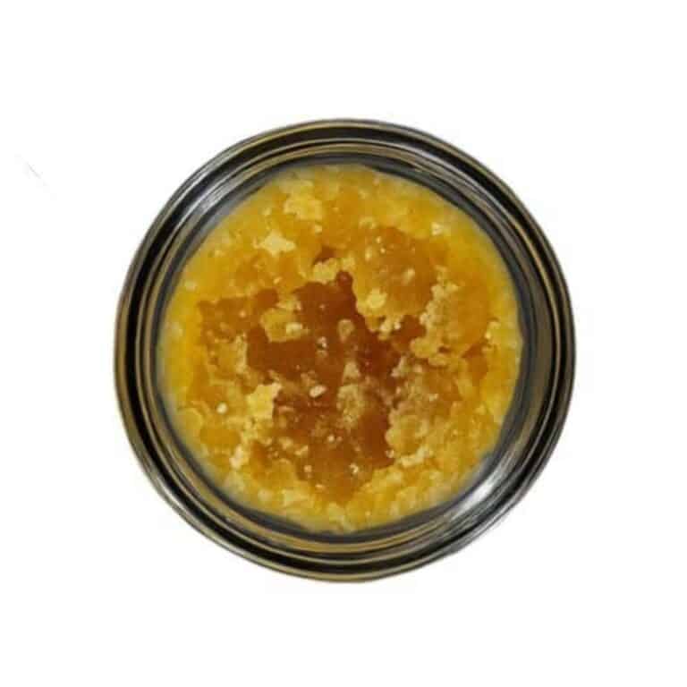 Open jar with golden, crumbly texture and granular consistency (close-up)