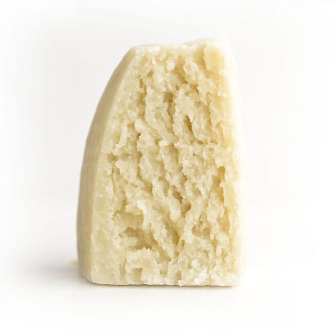 Photorealistic close-up of a wedge of aged crumbly cheese on a crisp white background for product display.