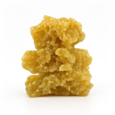 Golden-yellow cannabis crumble stacked in three uneven chunks on a crisp white background, showing detailed crystalline texture and natural colour variation.