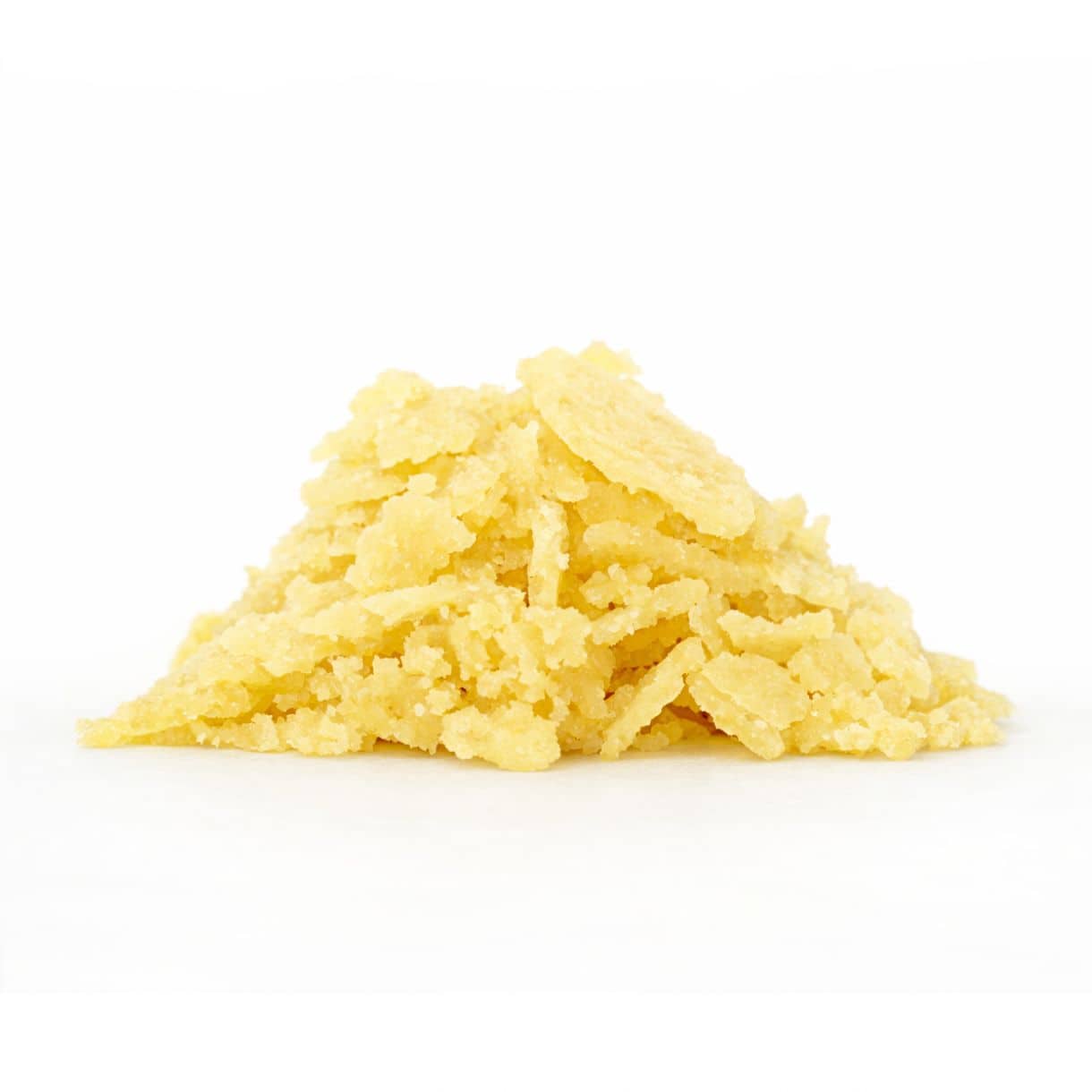Photorealistic close-up of pale yellow sugar wax flakes arranged in a small mound on a white background.