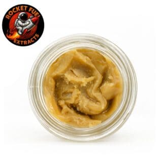 Top-down view of a glass jar containing golden-brown cannabis concentrate with a smooth, whipped texture on a crisp white background.