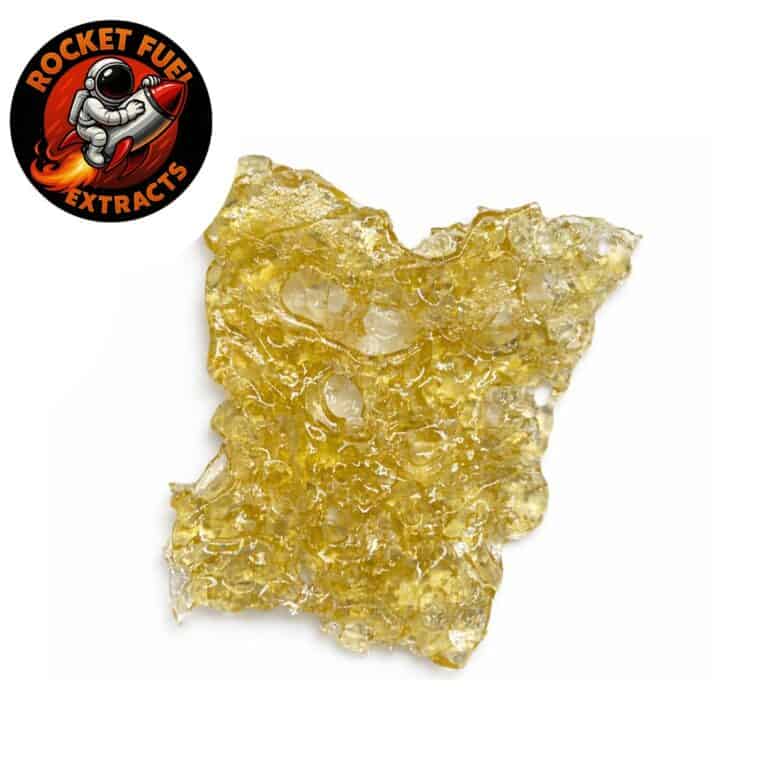 Golden cannabis shatter extract with translucent, glass-like texture on a crisp white background, Rocket Fuel Extracts logo visible in the corner