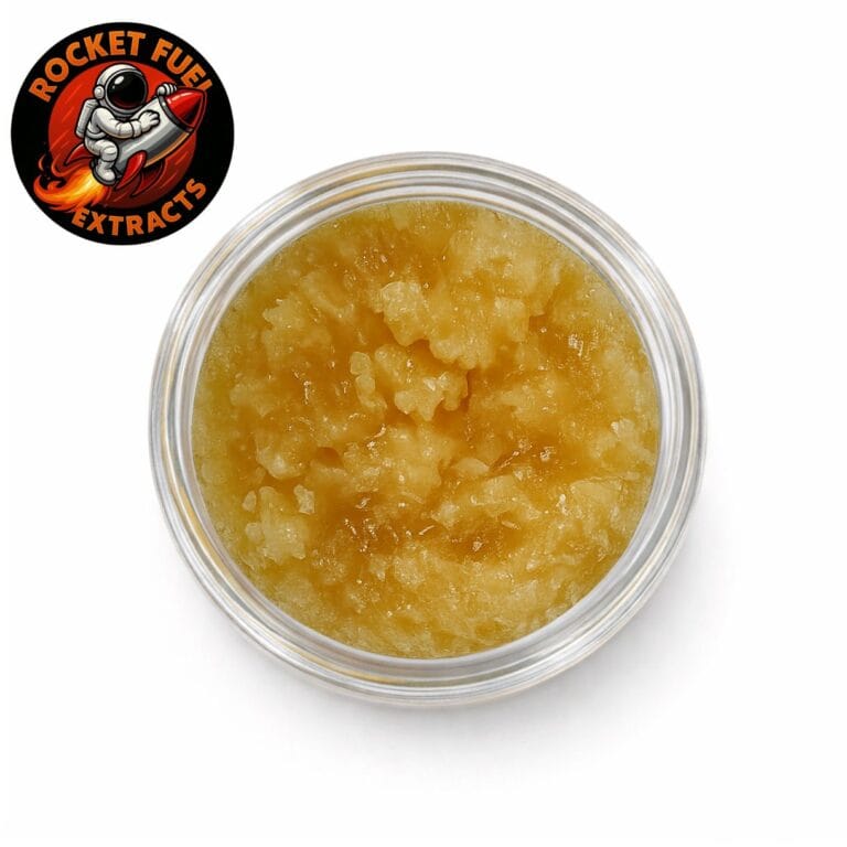 Close-up of Rocket Extracts cannabis concentrate with golden, crystalline texture in a round container on a white background