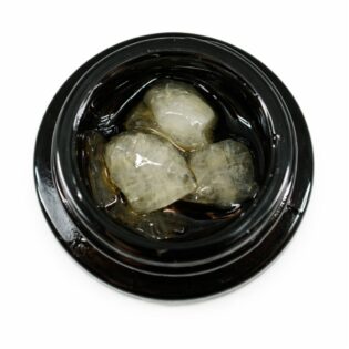Close-up of cannabis concentrate diamonds in sauce inside a black extract jar on a white background