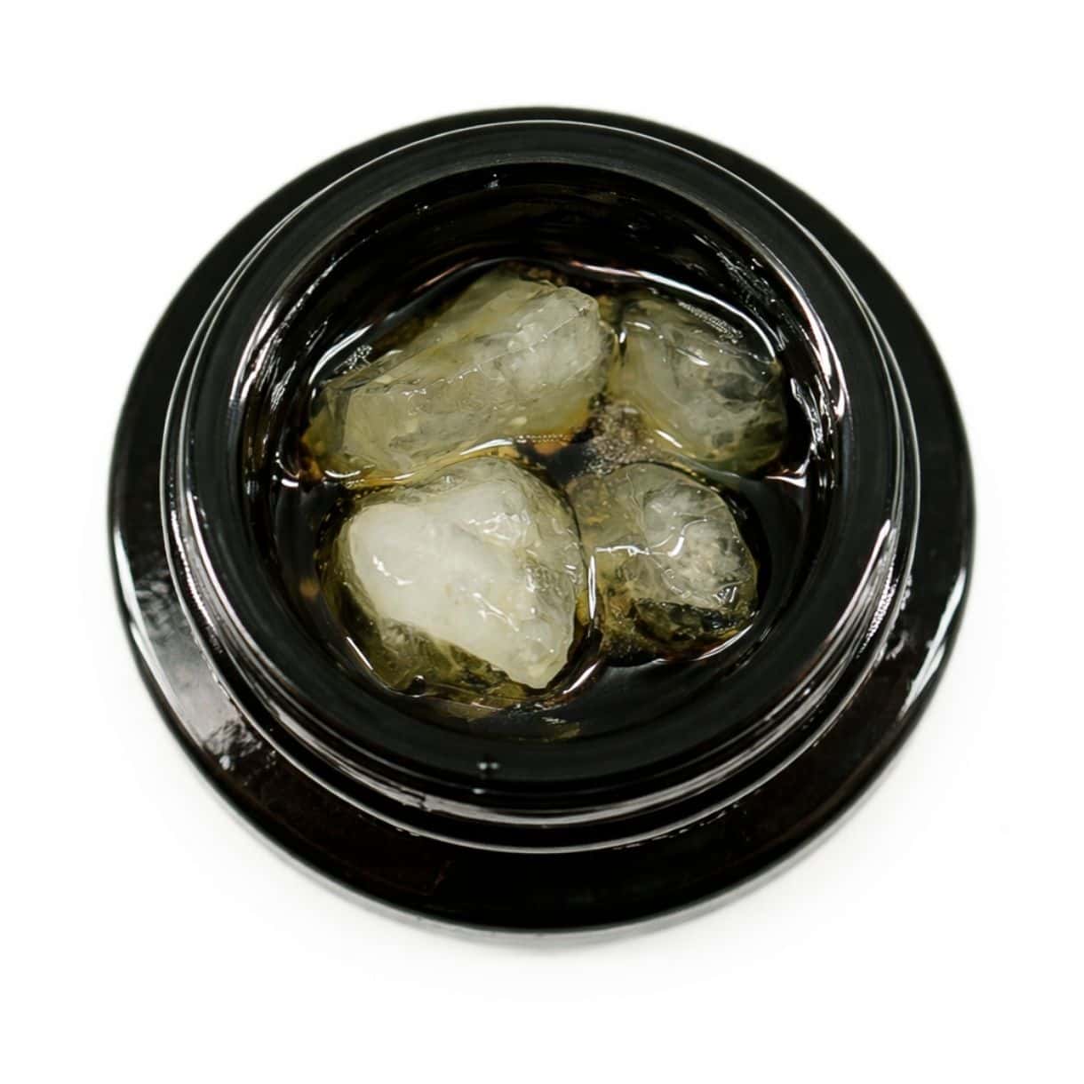 Close-up of cannabis concentrate diamonds in sauce inside a black extract jar on a white background