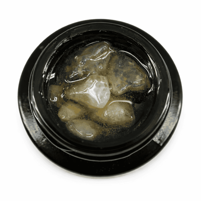 Close-up of cannabis concentrate diamonds in sauce inside a black extract jar on a white background