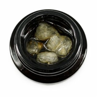 Close-up of cannabis concentrate diamonds in sauce inside a black extract jar on a white background
