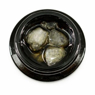 Close-up of cannabis concentrate diamonds in sauce inside a black extract jar on a white background