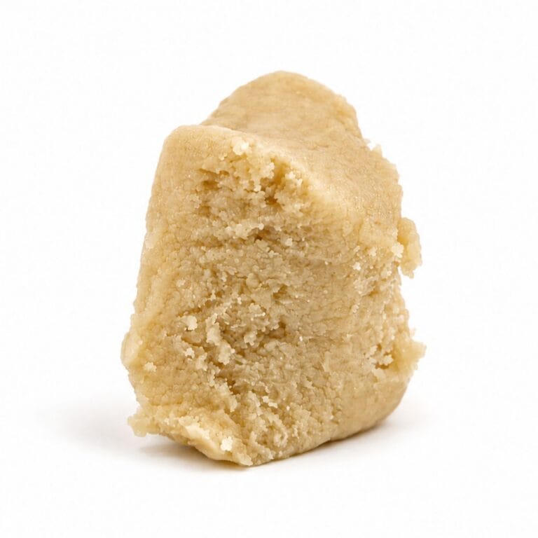 Premium light-golden cannabis concentrate with a smooth, dense texture, displayed as a sliced nug-style extract on a clean white background.
