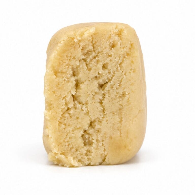 Premium light-golden cannabis concentrate with a smooth, dense texture, displayed as a sliced nug-style extract on a clean white background.