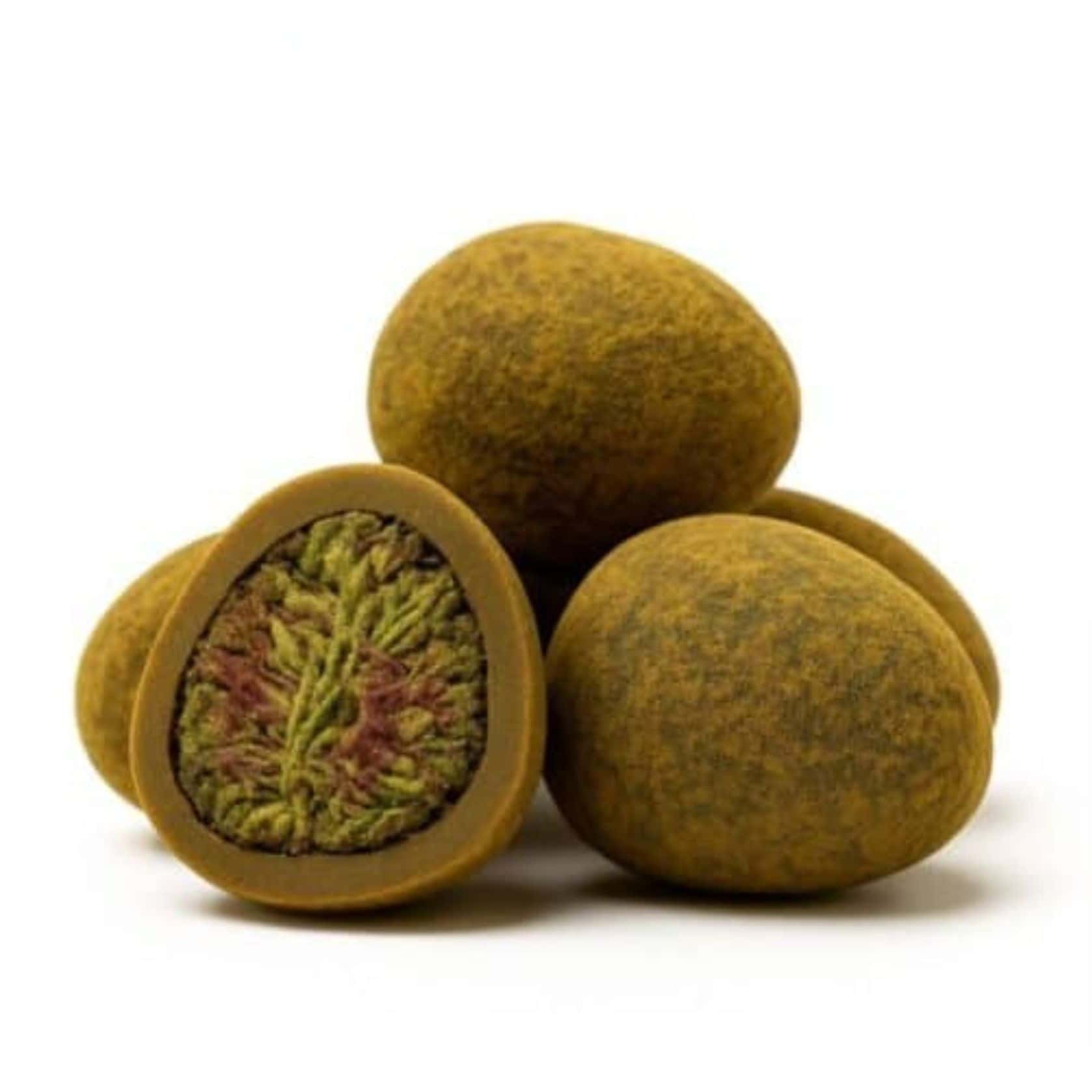 Close-up of round cannabis hash balls with one cut open to reveal a dense green and purple cannabis flower center.