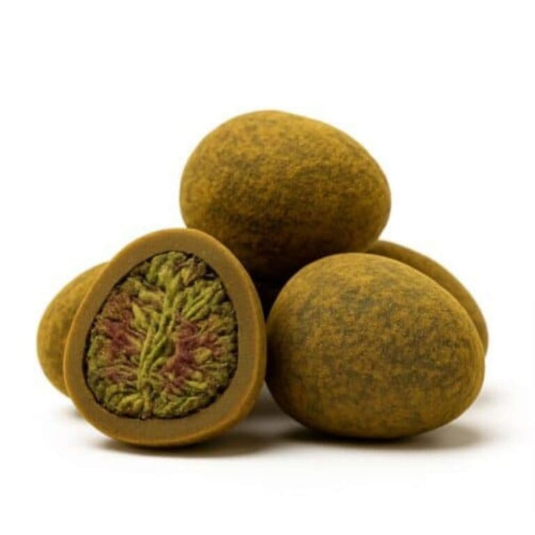 Close-up of round cannabis hash balls with one cut open to reveal a dense green and purple cannabis flower center.