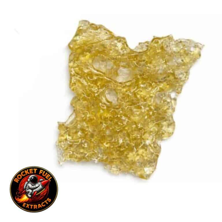 Close-up of a translucent golden cannabis concentrate slab with a porous, lace-like texture on a crisp white background.