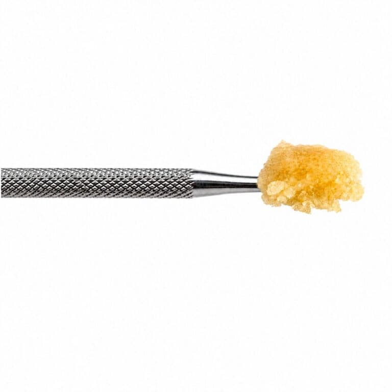 Ice Cream Cake Live Resin cannabis concentrate on a stainless steel dab tool with a golden terpene-rich extract against a white background.