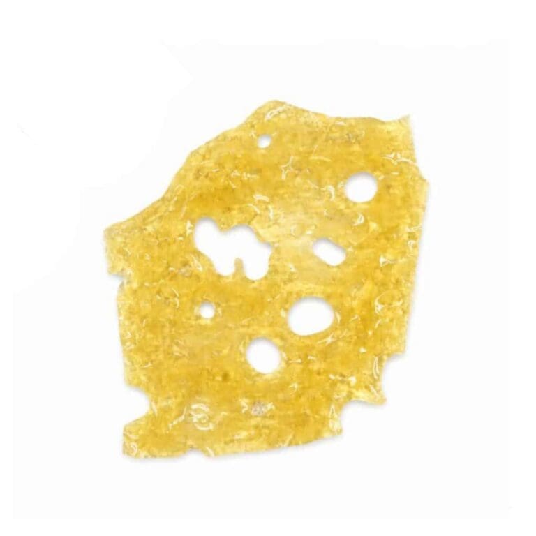 Close-up of a translucent golden cannabis concentrate slab with a porous, lace-like texture on a crisp white background.