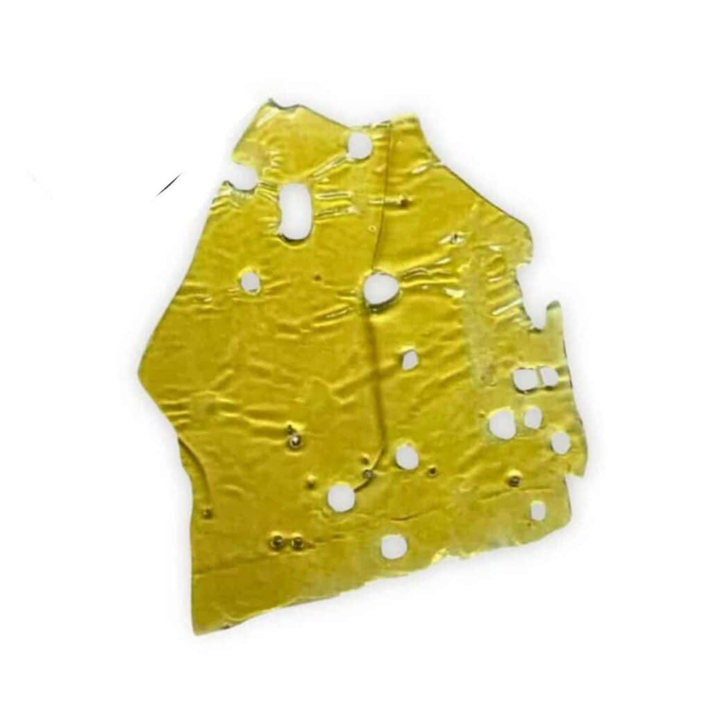 Close-up of a translucent golden cannabis concentrate slab with a porous, lace-like texture on a crisp white background.