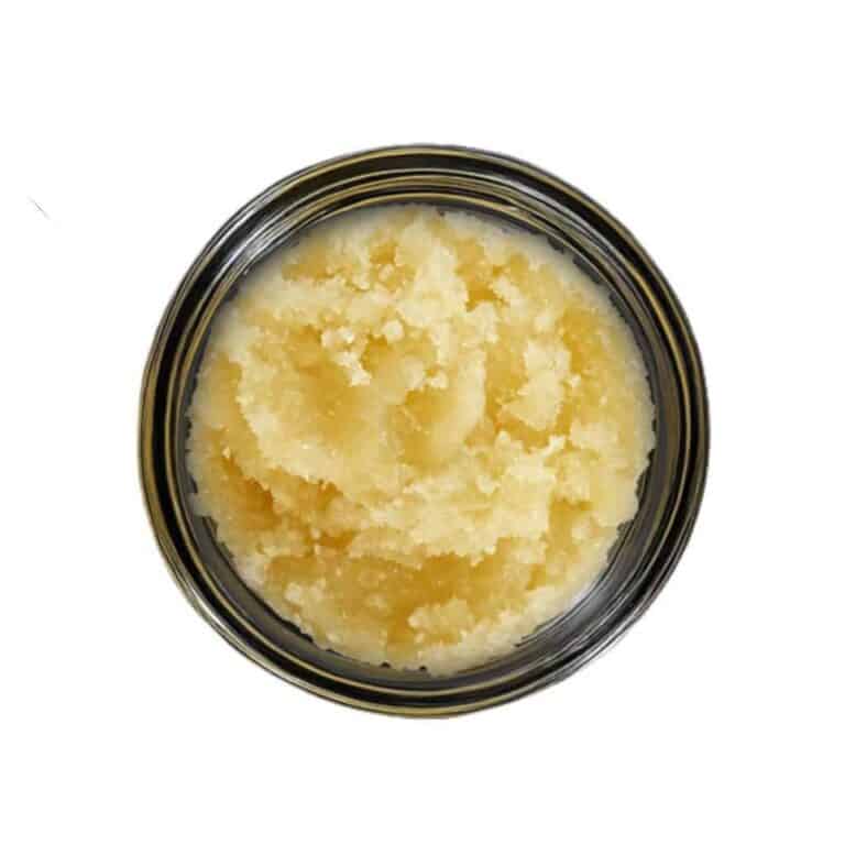 Open container of light-golden cannabis concentrate with a creamy, whipped texture on a white background.