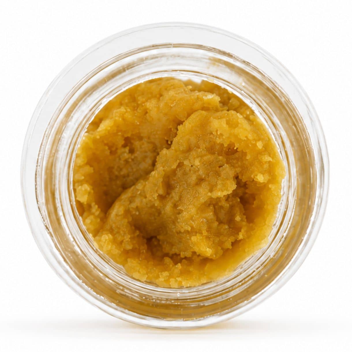 Un récipient ouvert contenant un concentré de cannabis de couleur dorée claire, à la texture crémeuse et mousseuse, sur fond blanc.